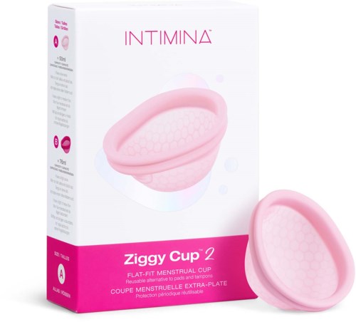 Eine pinke flexible Menstruationskappe vor einer weißen Schachtel mit pinken und lilafarbenen Details. Die Schachtel sagt 'Ziggy Cup 2' und 'INTIMINA.'