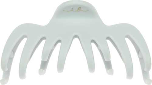 A white octopus-shaped hair clip with a gold signature on top.