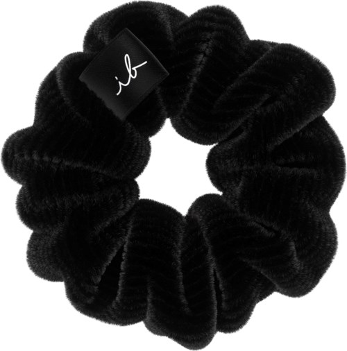 A black, fuzzy scrunchie with a small tag that has a signature design.