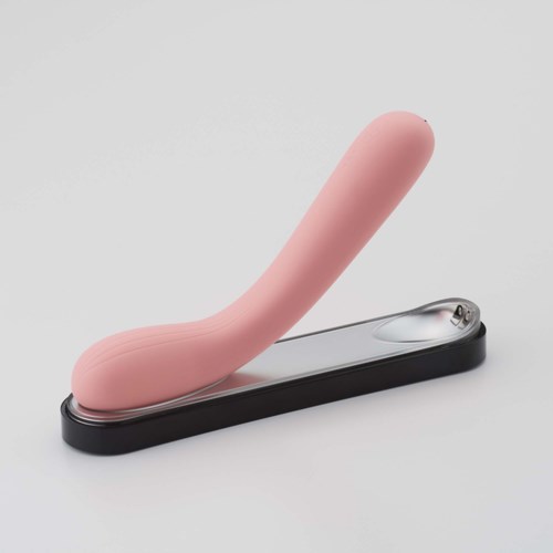 Ein rosa, gebogener Gegenstand auf einer schwarzen und grauen Basis, ähnlich einem Massagegerät.