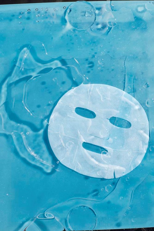 Een wit gezichtsmasker drijft in water met bellen eromheen, voor een rustgevende spa-gevoel.