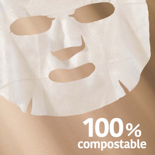 Een wit gezichtsmasker met oog- en mondgaten, ligt op een oppervlak, met tekst die zegt dat hij 100% composteerbaar is.