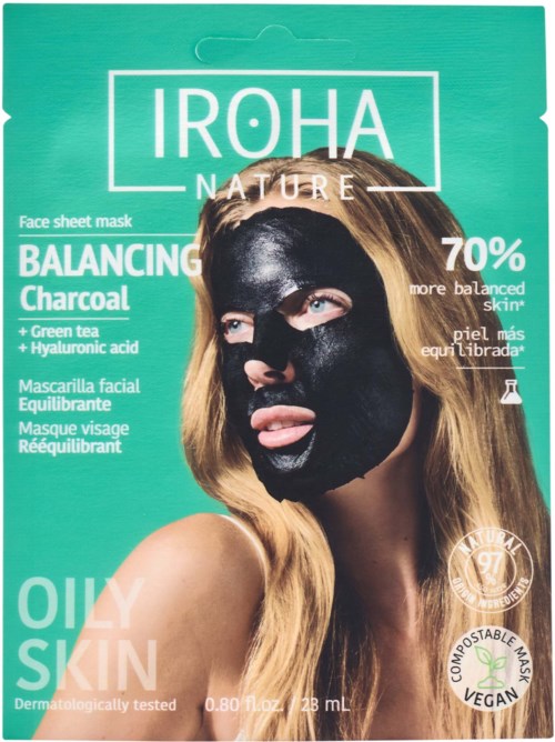 Een vrouw met lang haar draagt een zwart gezichtsmasker en houdt haar tong uit, op een heldergroene achtergrond.