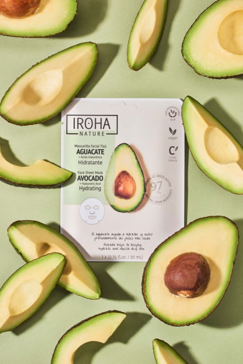 Een gezichtsmaskerverpakking omgeven door gesneden avocado's op een lichtgroene achtergrond.