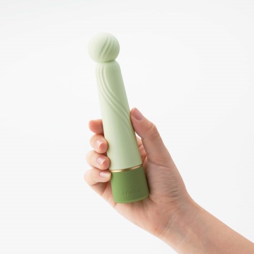 Eine Hand hält ein langes, grünes und weißes Gesichtspflege- oder Massagerät mit einer kugelförmigen Oberseite.