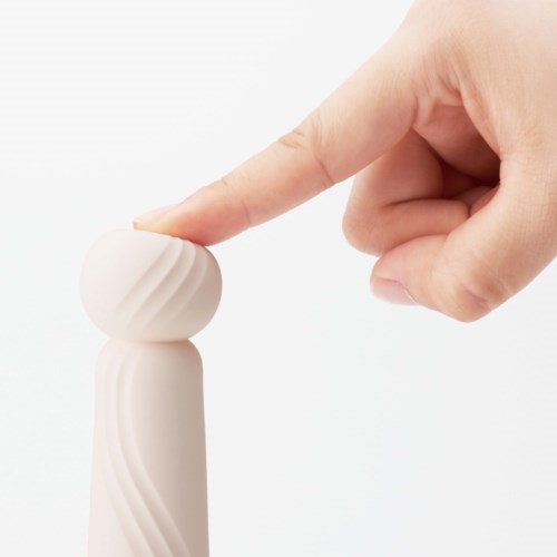 Eine Hand berührt einen kleinen, weißen, runden Gegenstand mit gebogenen Linien auf weißem Hintergrund.