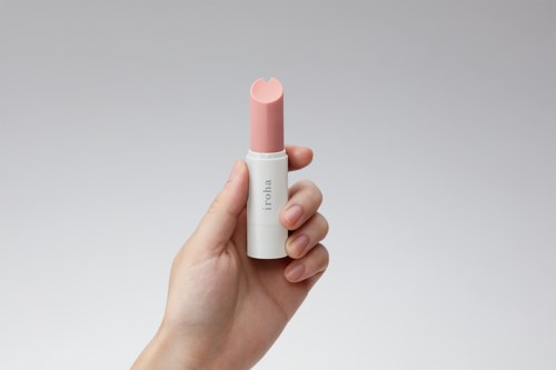 A hand holds a pink and white lipstick-like object, with a simple background.