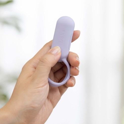 Eine Hand hält ein kleines, lila Silikon-Gerät mit Schlaufe, beschriftet "mobi". Der Hintergrund ist weiß und verschwommen.