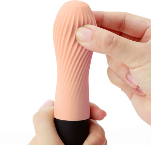 A person is holding a pink, textured, finger-shaped object with a black base.