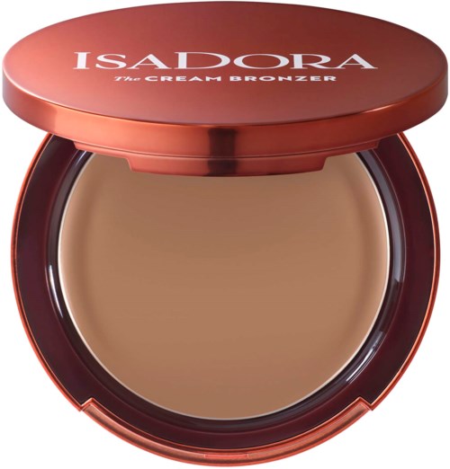 A compact with a brown cosmetic product called IsaDora Cream Bronzer inside. The compact has a shiny, reddish surface.
