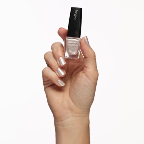 En hand håller en flaska nagellack i beige färg med svart lock och vit text, mot en vit bakgrund.