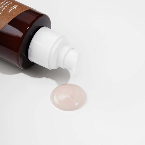 Een bruine fles met een witte druppelk Ap, met een kleine hoeveelheid lichtroze gel of lotion op een witte ondergrond.