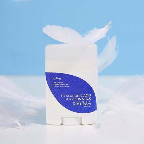 Een witte container met een blauwe label, omgeven door witte veren, geplaatst op een lichte achtergrond.