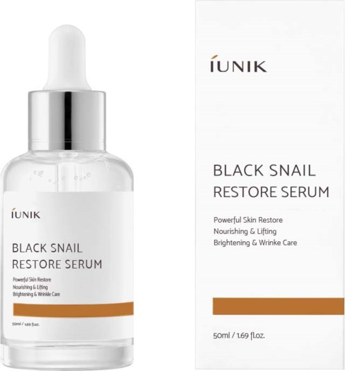 Een heldere glazen fles met pipet bevat Black Snail Restore Serum, naast de witte doos met productinformatie.
