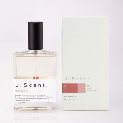 En tydlig parfymflaska med svart lock bredvid en vit förpackning märkt J-scent W Hakka, 50 ml.