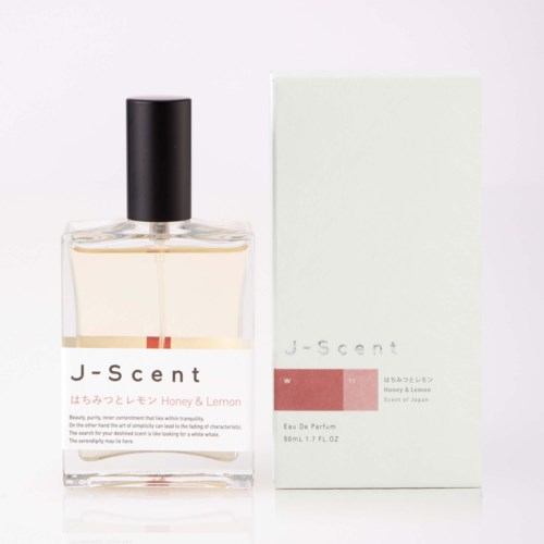 En parfymflaska märkt J-Scent Honey & Lemon bredvid dess förpackningslåda.