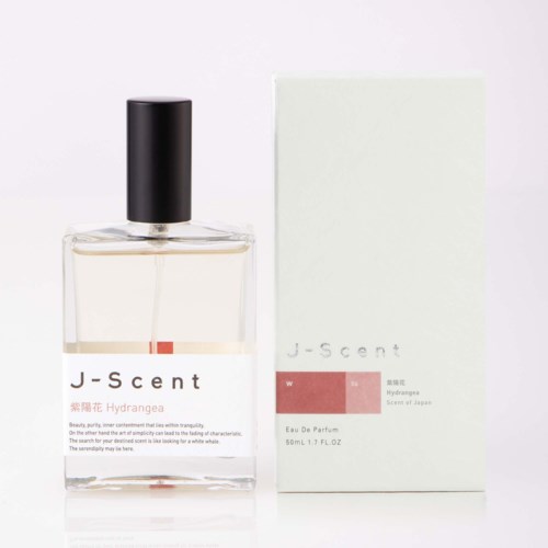 En parfyllflaska med svart lock bredvid en vit box med rosa och grå etiketter som visar J-scent Hydrangea Eau De Parfum.