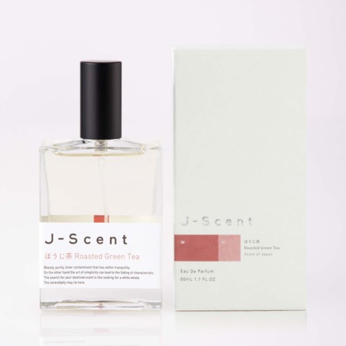 En tydlig parfymflaska i glas med svart lock bredvid ett vitt förpackningskort med texten J-scent och Roast Green Tea doft.