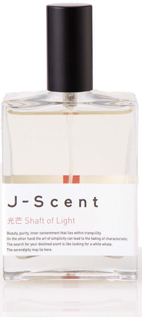 En transparent parfymflaska i glas med svart lock och vit etikett, innehållande ljusfärgad vätska. J-Scent Shaft of Light etikett med text.