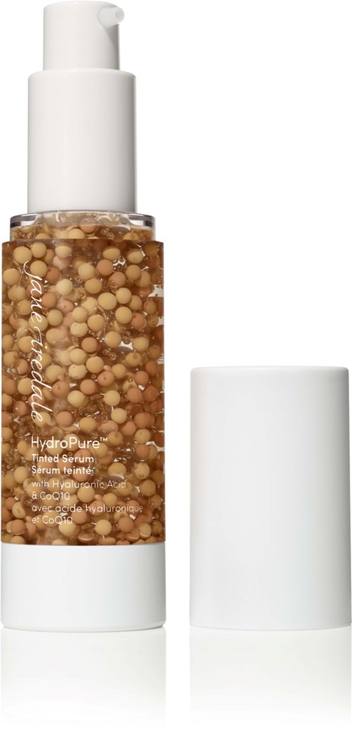 En tydlig flaska med beige pärlor inuti och en vit pump, troligtvis en hudvårdsserum med vit kork.