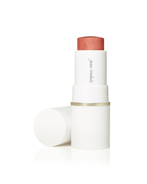 A stick of lipstick with a pinkish color, in a white container with a lid lying beside it.