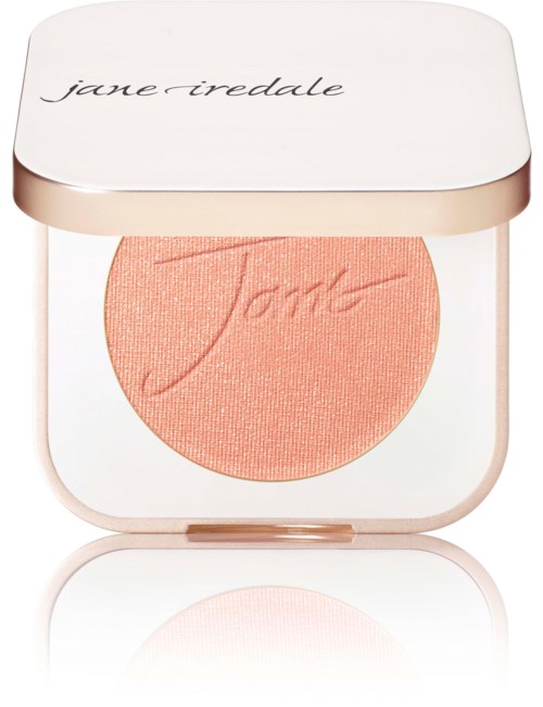 En rund, persikfärgad makeuprouge i ett vitt fodral med guldkant, med 'jane iredale' på locket.