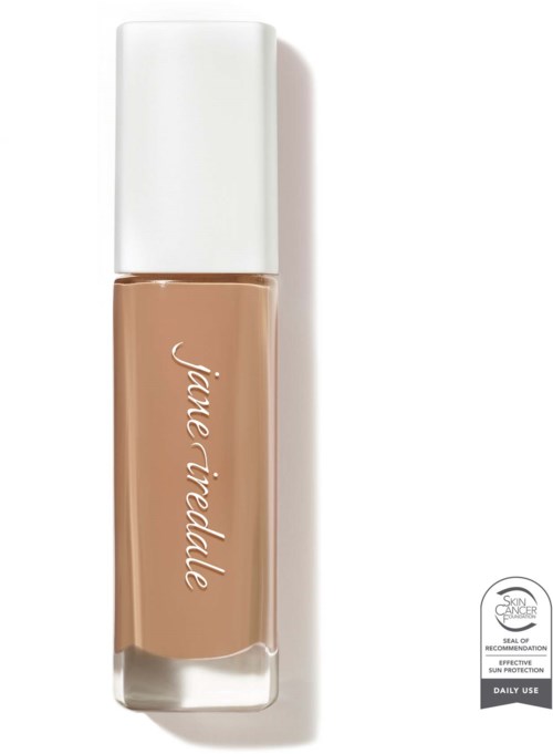 A bottle of liquid foundation with a white cap and beige color. The brand name is written on it.