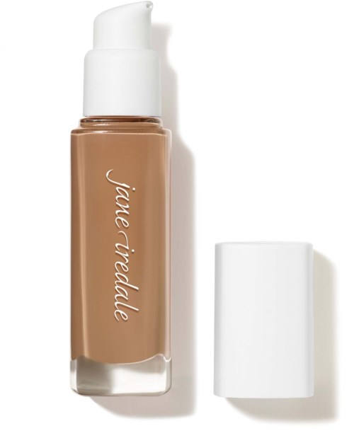 A beige liquid foundation bottle with a white cap and label, with the cap placed beside it.
