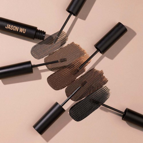 Vier vloeibare eyeliners in verschillende kleuren liggen op een vlakke ondergrond, sommige met kwastharen die kleur laten zien.