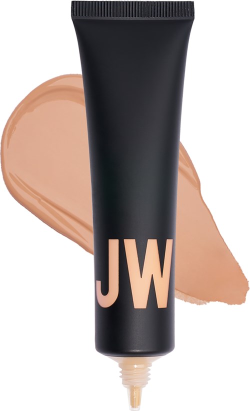 En svart tub med 'JW' tryckt, med beige makeup bakom, troligtvis en concealer eller foundation.