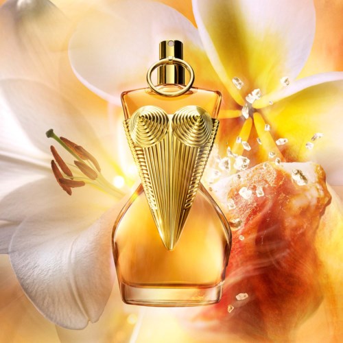 Een parfumbotje met gouden details, omgeven door witte en gele bloemen en suikerkristallen op de achtergrond.