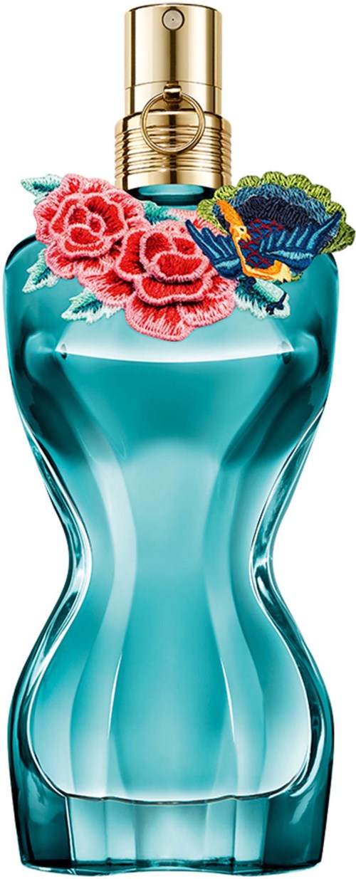 Een parfumfles met roze bloemen en een kleurrijk geborduurd lapje rond de hals.