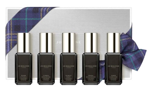 Five bottles of dark nail polish with silver caps, arranged in front of a box wrapped with blue plaid fabric.