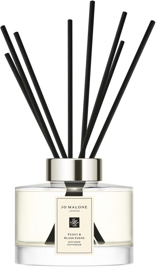 Tuoksuetsylinteri, jossa mustia pikkutikkuja ja etiketti Jo Malone Peony & Blush Suede.