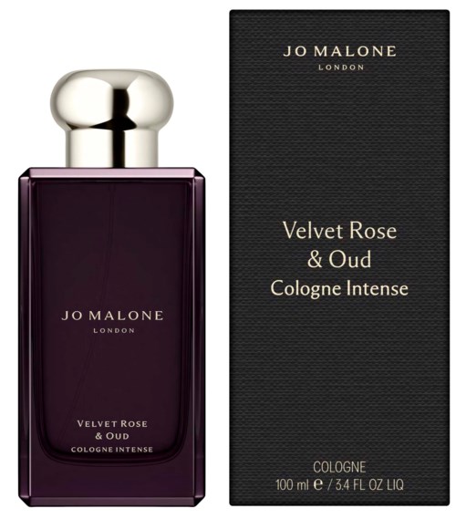 A perfume bottle with a dark purple color and a large silver cap, beside its black box label.