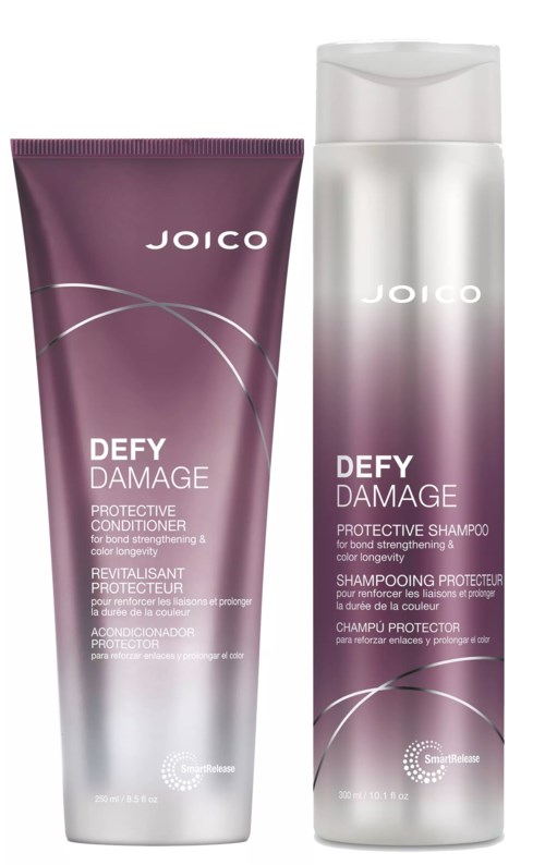 Das Bild zeigt eine lilafarbene Tube und eine hohe silberne Flasche, beide mit der Aufschrift 'JOICO DEFY DAMAGE' Haarpflegeprodukte, eine Spülung und ein Shampoo.