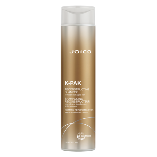 Eine lange, goldfarbene Flasche mit weißem Deckel, beschriftet 'JOICO K-PAK RECONSTRUCTING SHAMPOO.'