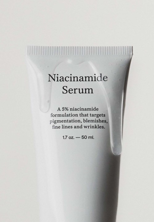 Een witte tube met niacinamide serum, 50 ml, met zwarte tekst over het doel en ingrediënten.