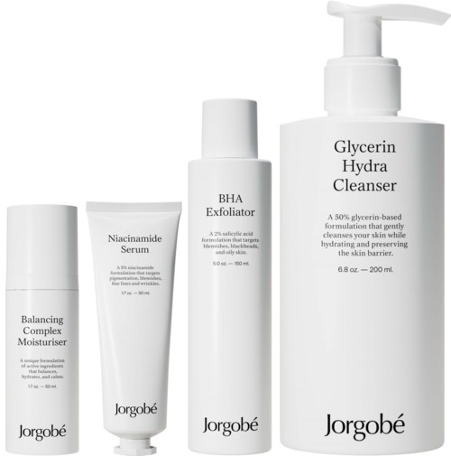 Vier huidverzorgingsproducten: vochtinbrengende crème, serum, exfoliant en reiniger, allemaal in witte flessen met zwarte tekst.