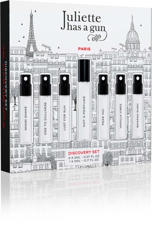 Een parfumtestset met zes kleine bottles en één grote, met verschillende geuren, tegen een stadshorizont.