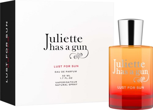 De afbeelding toont een parfumfles en doos met het label 'Juliette Has a Gun Lust for Sun'. De fles is oranje met een zilverkleurige dop.