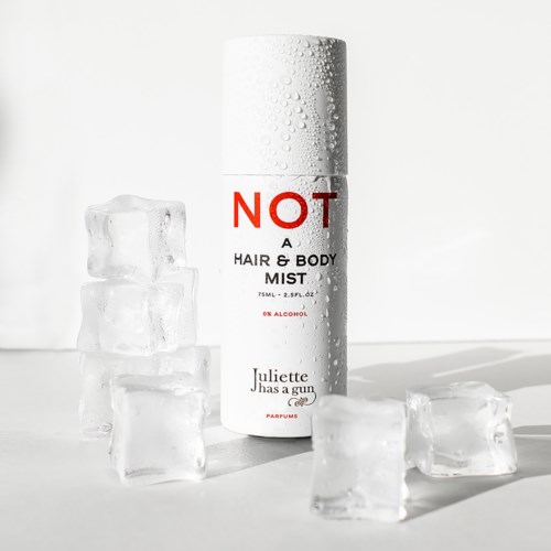 Een wit spuitbusje met 'NOT A HAIR & BODY MIST' erop, omringd door ijsblokjes.