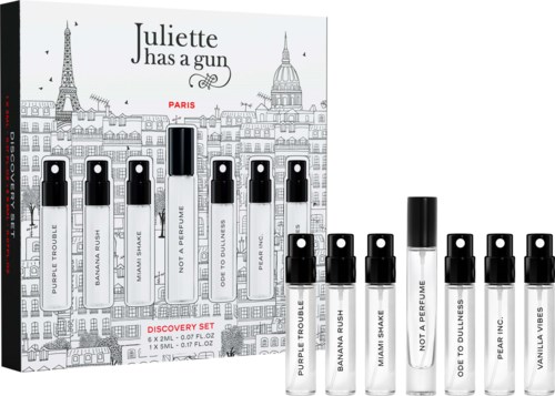 Set of ten perfume sample vials with black caps, displayed in front of black and white cityscape illustration, labeled with scent names.