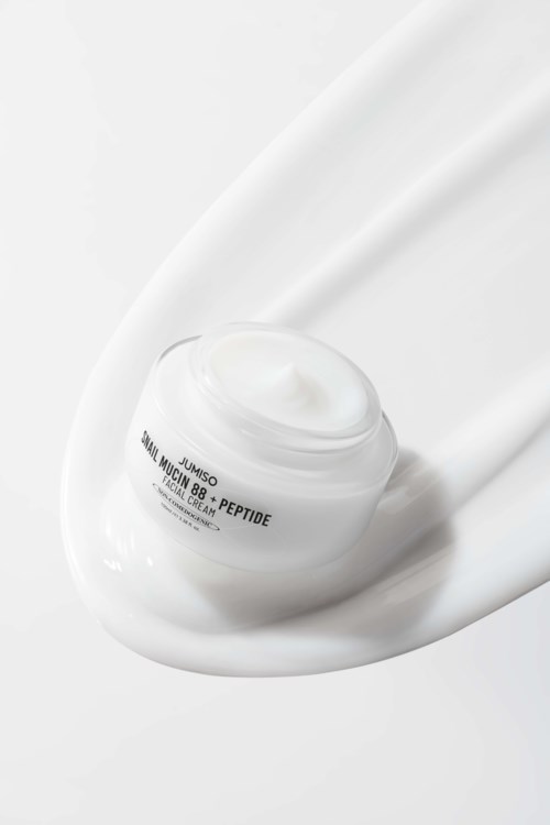 Een klein potje crème met label 'Sulwhasoo'. Crème verspreid op een witte ondergrond in een spiraal.