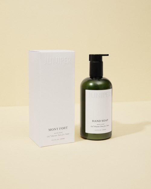 A green bottle of hand soap with a pump next to a white box on a light background.