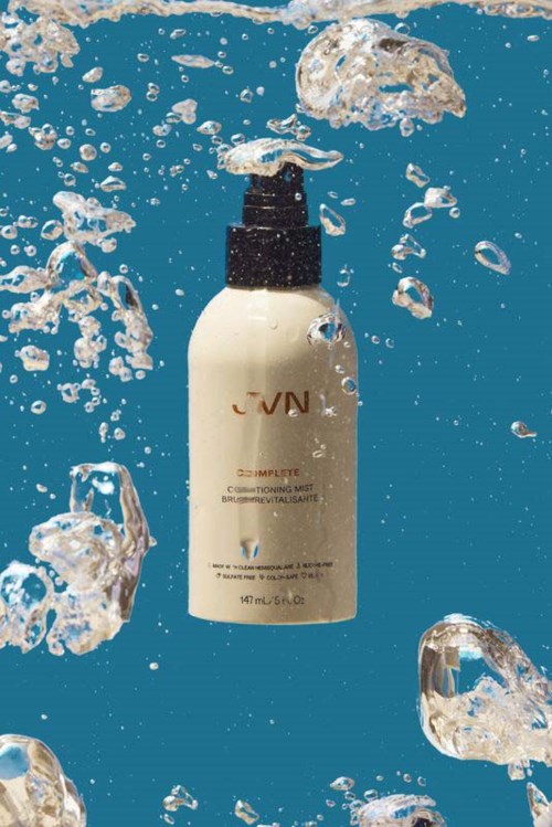 Eine JVN-Haarpflegeflasche, die im Wasser mit Blasen herumtaucht.