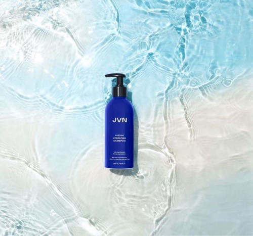 Eine blaue Shampooflasche schwimmt auf Wasser mit Wellen an einem Strand oder Pool.