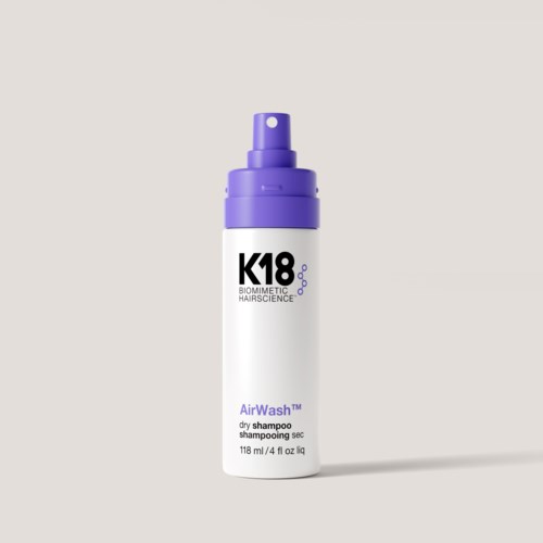 A white bottle with purple cap labeled K18 Biometric Hairscience and AirWah dry shampoo.