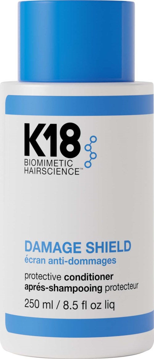 A white bottle with a blue cap and blue stripes. It is labeled K18 Damage Shield conditioner for hair.