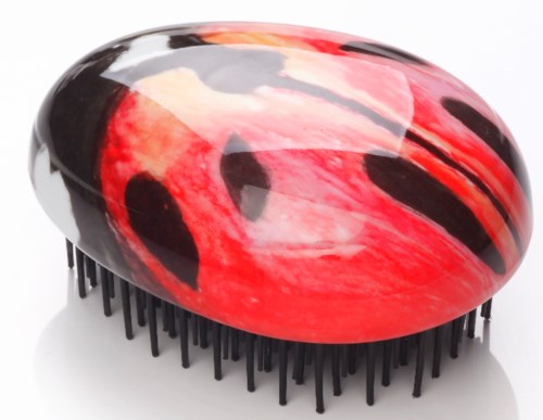 A round hairbrush with a red and black ladybug design and black bristles.